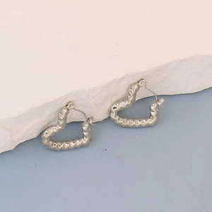Detail of silver heart-shaped earrings with crinkle texture and polished finish