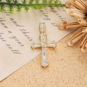 Detailed view of a gold cross pendant with baguette zircons and a heart center stone