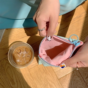 Close-up of light blue mini pouch with pink interior and round zipper puller