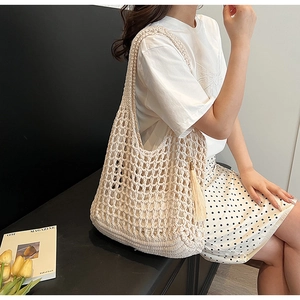 Detail showing beige hollow-out woven tote bag with matching tassel on model's shoulder