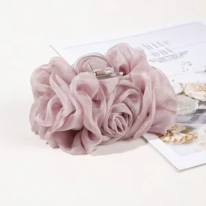 Macro detail of large dusty rose chiffon hair claw with elegant ruffled texture