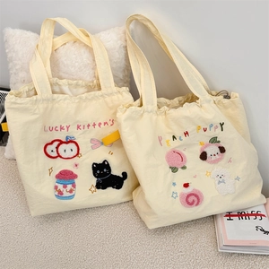 Detailed view of cream canvas tote featuring 3D towel embroidery and drawstring closure