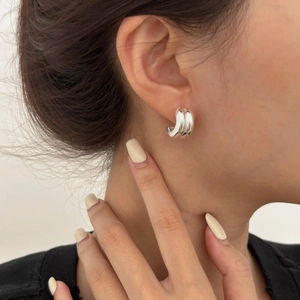 Detailed close-up of a minimalist C-shaped silver earring worn on an earlobe
