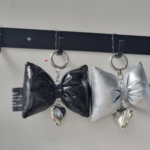 Macro detail of silver and black padded bow keychains with heart-shaped pendants