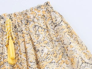 Detail of yellow floral print skirt with elastic waist and tassel drawstring cords