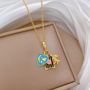 Macro detail of gold necklace with blue world map heart and tiny airplane pendants