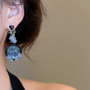 Dettaglio ravvicinato di un orecchino floreale in smalto blu con accenti di diamanti al lobo
