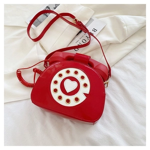 Detail of red vintage telephone shaped crossbody bag with rotary dial and heart detail