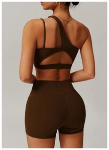 Detail of coffee brown one-shoulder sports bra with triangle back cutout and gym shorts