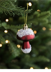 Detail of red mushroom Christmas ornament with white glitter on a festive tree branch