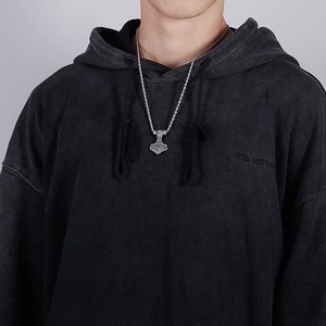 Close-up of a silver Thor's hammer pendant on a twisted chain worn by a male model