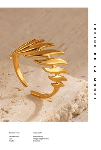 Close-up of 18K gold plated layered leaf ring on a stone base with warm lighting