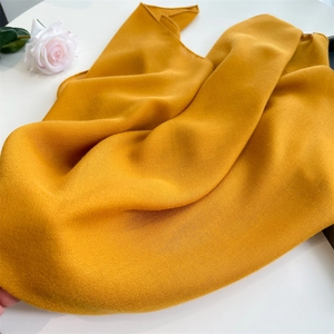 Detailed texture of lightweight yellow cotton linen scarf with soft folds and a pink rose