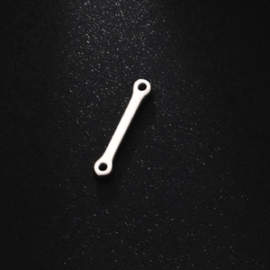 Macro shot of a silver bone-shaped stainless steel link connector with dual end holes