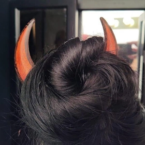Detailed view of burnt orange devil horn hair clips styled in a black updo hairstyle
