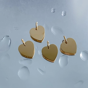 Close-up of polished gold heart-shaped stainless steel pendants with water droplets