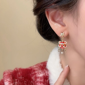 Detailed side view of festive red enamel lion dance earrings with gold stars and pearl charms