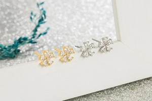 Close-up of five-petal flower stud earrings with clear zircons in gold and silver