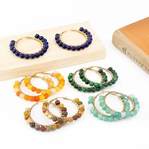 Detail of bohemian gold wire-wrapped hoop earrings featuring natural multi-color gemstones