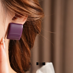 Orecchini a perno quadrati minimalisti in resina viola indossati su una modella