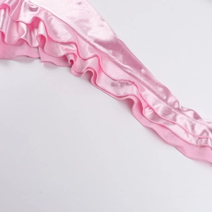 Dettaglio di volant multistrato su abito in raso rosa chiaro con trama setosa