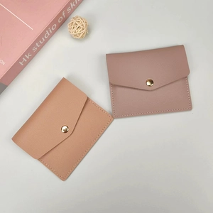Detail of slim leather card holders in tan and pink with gold snap button closure