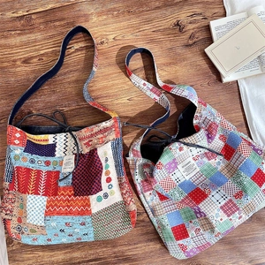 Detail of two boho patchwork canvas tote bags with drawstring closure on a wood floor