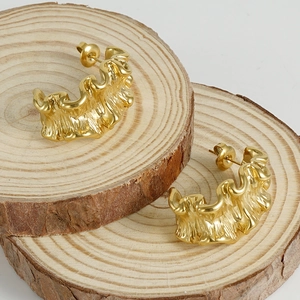 Detail of 18K gold-plated stainless steel earrings with molten lava texture on wood