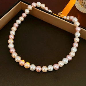 Detailed view of multi-color pearl necklace with gold clasp in a black gift box