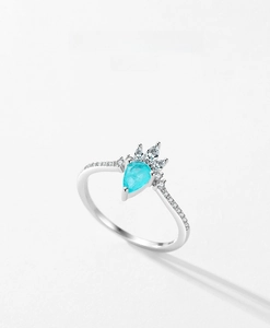 Detailed macro of a teardrop-shaped blue gemstone ring with crown style diamond accents