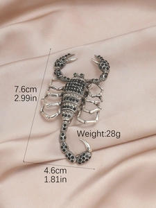 Macro detail of silver scorpion brooch with black and green rhinestones on silk