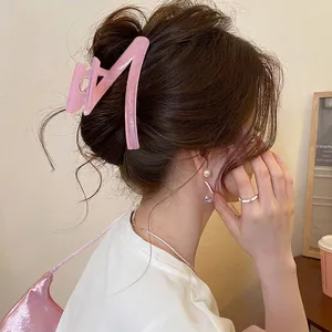 Pink translucent acrylic shark hair claw clip in Z-shape shown on model with updo hairstyle