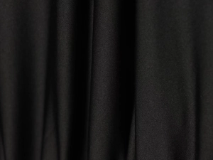 Close-up detail of high-quality black knit fabric texture and elegant soft drape of the dress