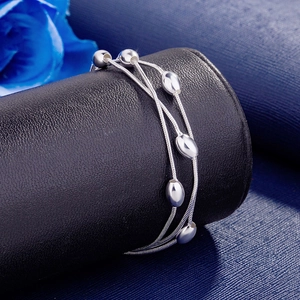 Detailed view of silver multi-layer bracelet with oval beads on a black leather stand