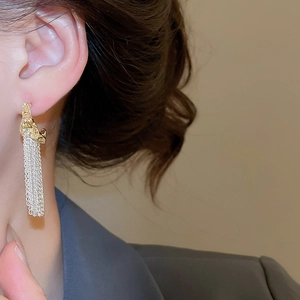 Close-up of elegant gold and silver tassel earrings on a model showing metal texture