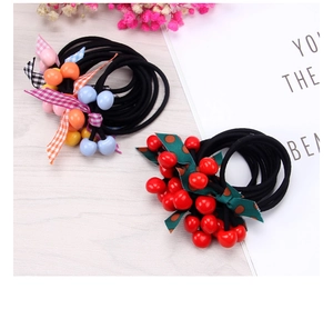 Detail of cherry beads and checkered bow hair ties on a rustic wooden background