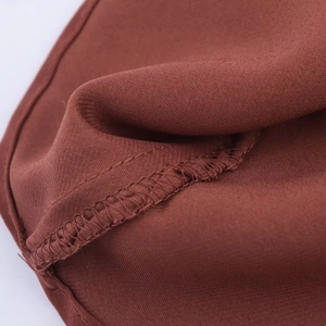 Gros plan sur le tissu en mousseline bordeaux montrant les coutures et la texture lisse