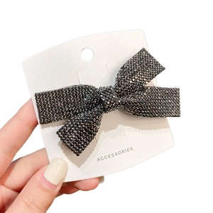 Elegant bow hair clip with dark grey rhinestones on a white display card for women