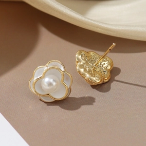 Elegant gold-trimmed white camellia flower stud earrings with pearl centers on silk