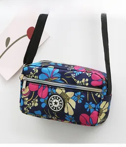 Detailed view of lightweight floral Oxford cloth crossbody bag with zipper pocket and sport logo