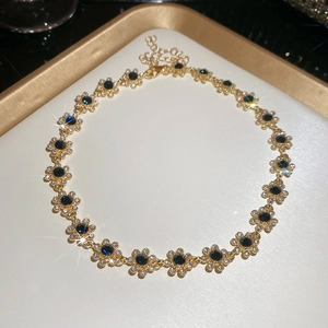 Detail of floral pendant necklace featuring dark blue gems and sparkling crystals
