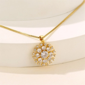 Gold snowflake pendant necklace with cubic zirconia on white display stand