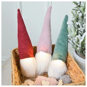 Close-up of three glowing Christmas gnomes with warm lights in a wicker basket decor