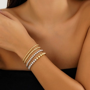 Close-up of gold and silver beaded bracelets with heart pendants on a model's wrist
