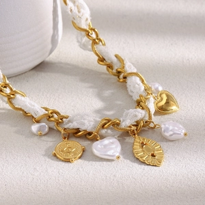 Detail of 18K gold plated chain necklace with lace ribbon and heart pearl pendants