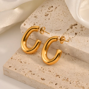 Close-up of high-polish 18K gold-plated U-shaped earrings on a stone platform