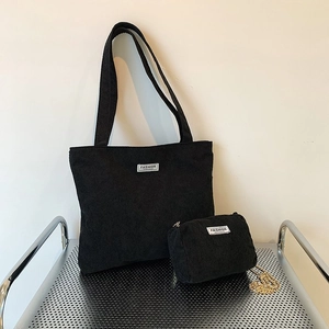 Large capacity black corduroy tote bag with matching pouch on minimalist metal shelf