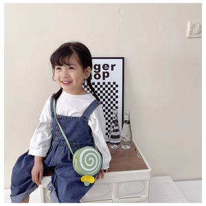 Detail of mint green round kids crossbody bag with lollipop print and yellow bow