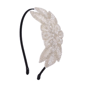 Macro shot of handmade beige beads and sequins in leaf patterns on a black fabric headband