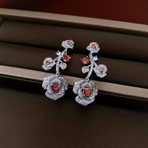 Macro shot of silver flower earrings with clear zircon and orange gemstone in jewelry box